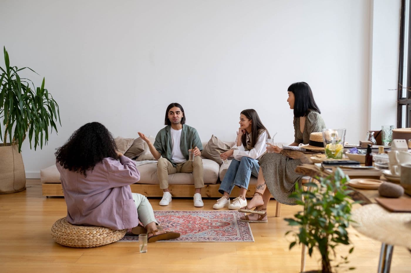 Eine gemischte Gruppe junger Menschen sitzt in einem Wohnzimmer entspannt zusammen