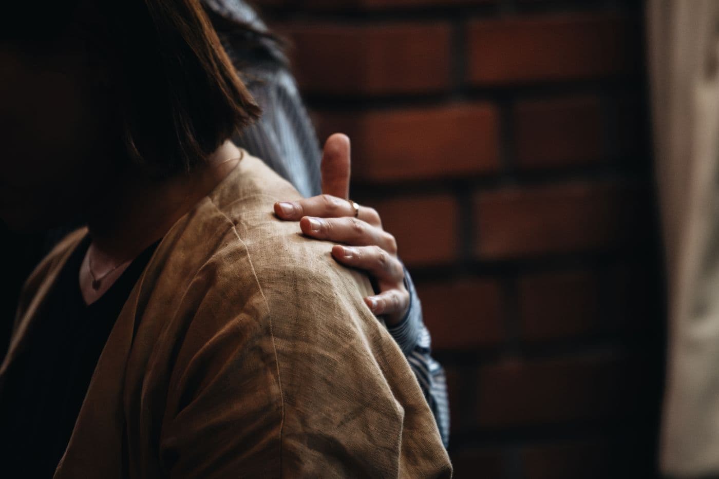 Eine Hand liegt tröstend auf der Schulter eines Menschen